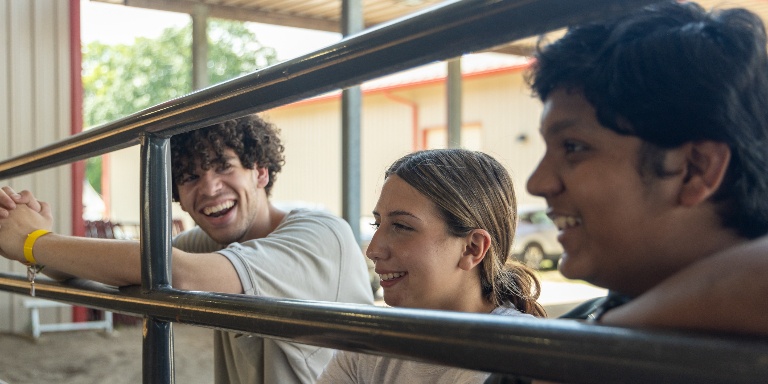 Students sitting by a metal bar.